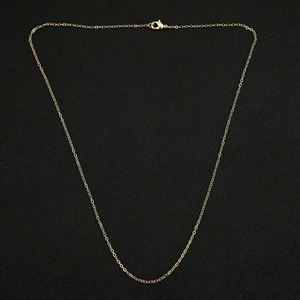 Close-up of golden O-link snake bone chain with lobster clasp on black background