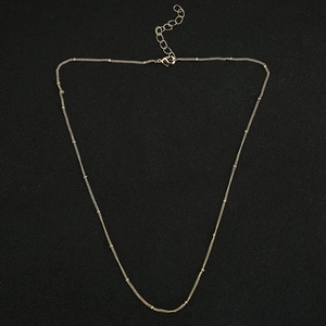 Detailed view of golden bead necklace chain with adjustable clasp on black background