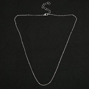 Detail of silver plated beaded O-chain necklace with lobster clasp on black background
