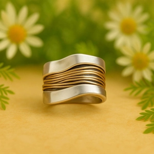 Macro detail of wave-designed wide ring with silver and gold intertwined metal textures