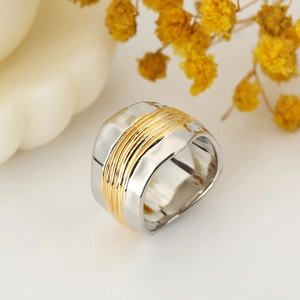 Modern wide wavy ring in silver with golden wire wrap detail on textured surface