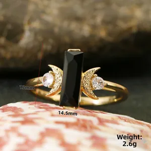 Macro d'une bague dorée avec pierre noire et croissants en zircon sur un coquillage