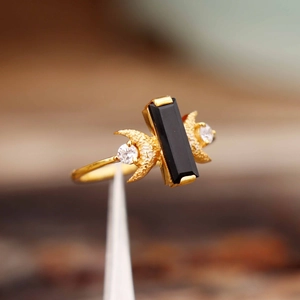 Vue macro d'une bague dorée en forme de croissant avec pierre noire et détails zircons