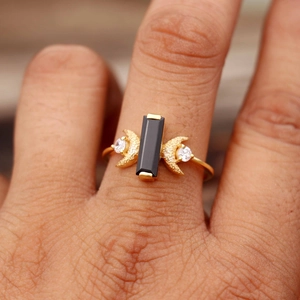 Vue rapprochée de la bague dorée avec pierre noire et détails de croissant de lune