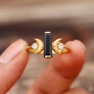 Détail macro bague dorée avec pierre d'obsidienne noire et accents de zircon brillant