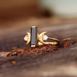 Détail macro d'une bague croissant de lune dorée avec pierre noire et éclats de zircon