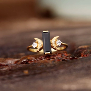 Gros plan sur bague dorée avec pierre noire et détails de croissant de lune sertis
