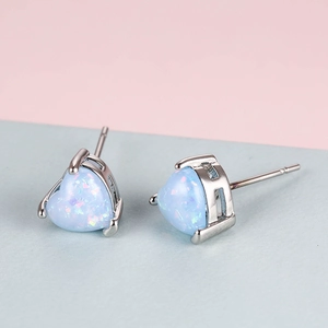 Macro detail of heart-shaped opal stud earrings with light blue iridescent finish