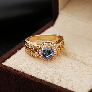 Close-up of luxury gold ring with a multi-colored round gemstone and pavé diamonds