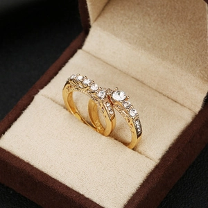 Elegante conjunto de dos anillos de boda bañados en oro con piedras de circón brillantes
