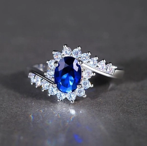 Anello di lusso con zaffiro blu ovale e halo di zirconi su fascia argentata
