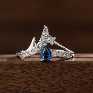 Detailaufnahme des Kronenrings mit blauem Saphir im Birnenschliff und weißen Diamanten