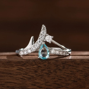 Makroaufnahme eines kronenförmigen V-Rings mit hellblauem Saphir und weißen Zirkonias