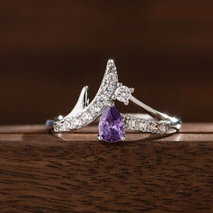 Makroaufnahme von V-förmigem Kronenring mit lila tropfenförmigem Edelstein und Diamanten