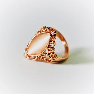 Close-up of vintage rose gold ring featuring a pink marquise opal and filigree patterns