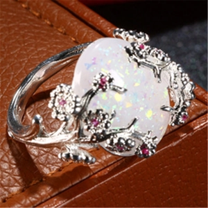 Macro shot of silver flower vine ring featuring a large white opal and pink crystals