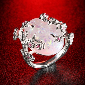 Floral vine silver ring with oval pink opal and red diamond accents on red background