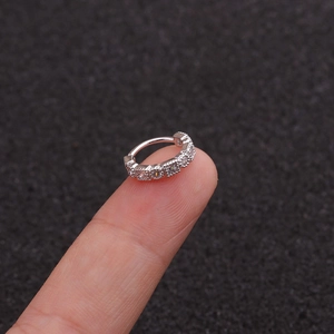 Gros plan d'une bague d'oreille en argent s925 avec zircons posée sur le bout du doigt