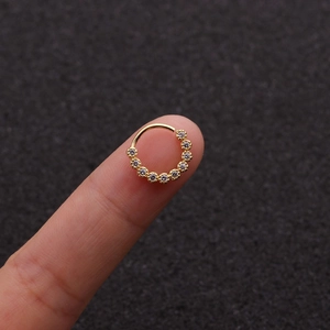 Gros plan d'une boucle d'oreille dorée avec zircons sur le bout du doigt pour la taille