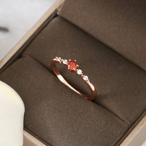 Close-up of a rose gold ring with a round ruby and diamonds in a velvet box