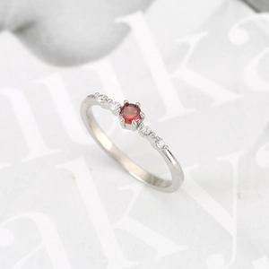 Macro detail of a silver ring with a round red ruby stone and white side diamonds