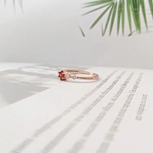 Detailed macro view of a rose gold ring with a round ruby center stone and clear side diamonds