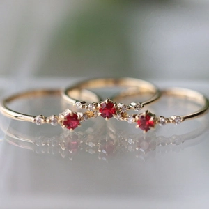 Three-piece gold plated ruby ring set with white diamonds on reflective surface