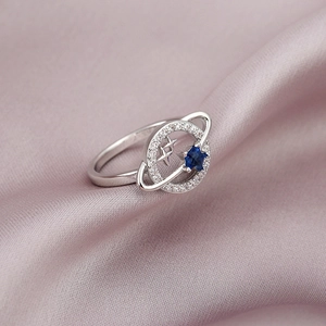 S925 Silber Planetenring mit blauem Sternstein und Zirkonia auf lila Seidenhintergrund