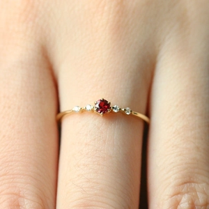 Macro shot of gold plated copper ring featuring a ruby center stone and white zircon accents