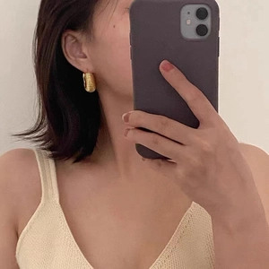 Boucles d'oreilles créoles dorées avec design torsadé portées par un mannequin