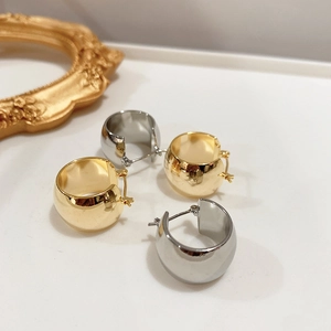 Boucles d'oreilles épaisses en or et argent poli sur un fond de style minimaliste