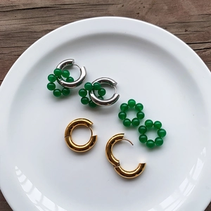 Titanium steel emerald bead earrings in gold and silver finish on white ceramic tray