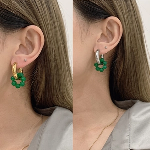 Detail of vintage emerald green bead drop earrings in gold and silver finish on model