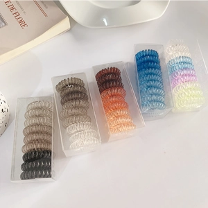 Close-up of spiral hair ties in transparent storage box with diverse gradient colors