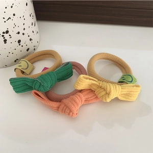 Détail de chouchous à nœuds côtelés avec étiquette smiley en vert, jaune, rose, orange