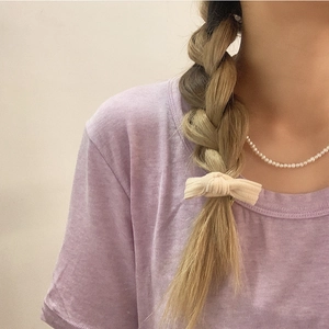 Élastique à cheveux beige avec nœud en velours côtelé sur une coiffure de tresse