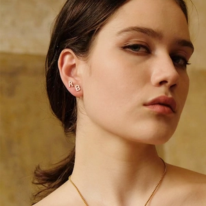 Close-up of asymmetric 925 silver earrings with sparkling zirconia letters R and B
