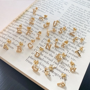 Macro shot of 925 silver needle gold letter stud earrings with cubic zirconia on book pages