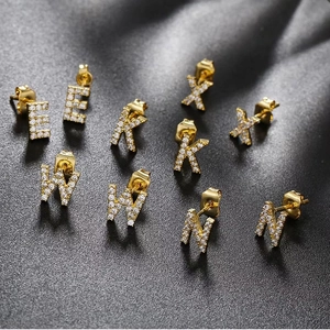 Close-up of gold letter earrings E, K, X, W, M with sparkling micro-pave zircons