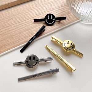 Minimalist metal smile hair clip set in gold, silver and black on wooden surface