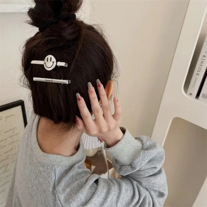 Close-up of silver metal smile hair clips set worn on brunette hair with sleek finish