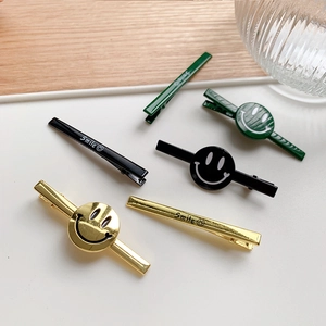 Detailed macro view of metal smiley face hair clips in green, black and gold finishes