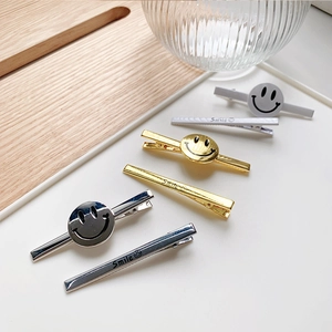 Detail of metal smile hair clips in gold, silver and grey finish with smile engraving