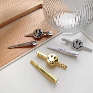 Detail view of gold, silver and white smiley face hair clip set on a wooden tray