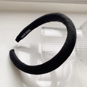Détail de l'étiquette HAND MADE sur un serre-tête épais en maille noire rembourré
