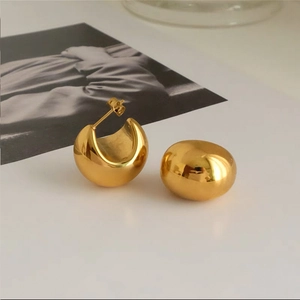 Macro-opname van minimalistische holle gouden bolletjes oorbellen met spiegelglans
