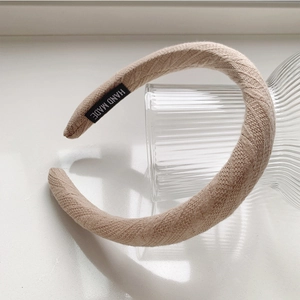 Détail du serre-tête tricoté beige avec étiquette Hand Made et texture tissée épaisse