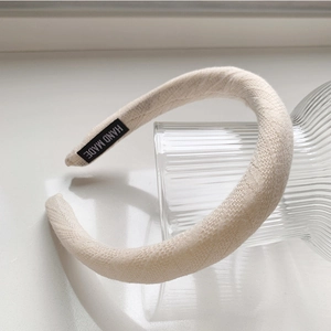 Détail du serre-tête rembourré en tricot crème avec une étiquette tissée Hand Made