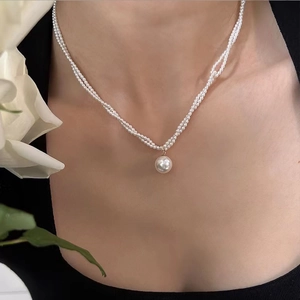 Elegante dreireihige kleine Perlenkette mit großem Anhänger an einem weiblichen Model