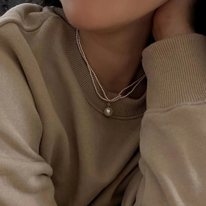 Detailansicht der doppellagigen Perlenkette mit 14k Goldkette am Hals einer Frau